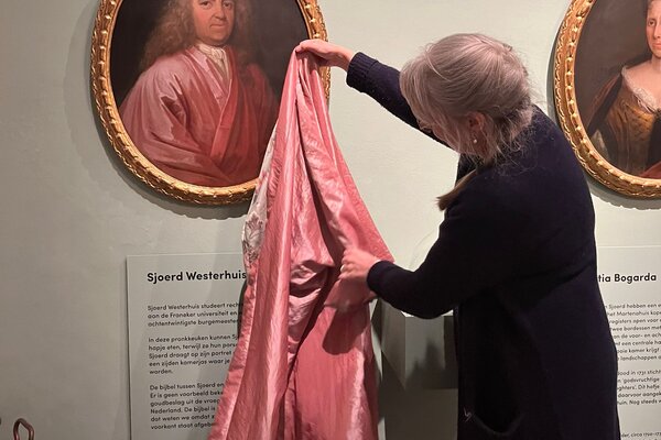 Hanneke controleert de kleur van de nagemaakte Japonse rok met het origineel afgebeeld op het portret van Sjoerd Westerhuis.
