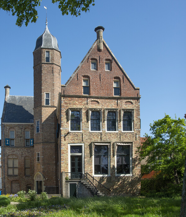 Close-up van het bordes van Museum Martena met de toren die belicht wordt door de zon.